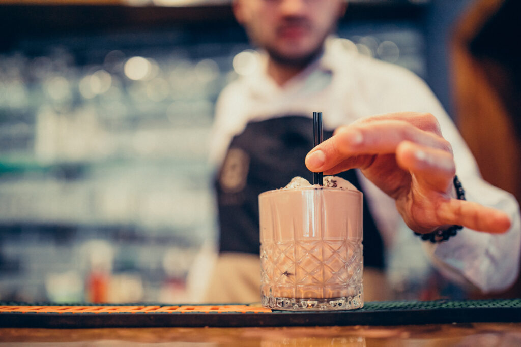 Handsome bartender making drinking and cocktails at a counter